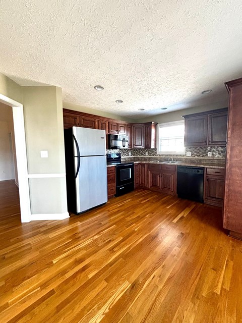 A kitchen with wooden floors and dark brown cabinets.