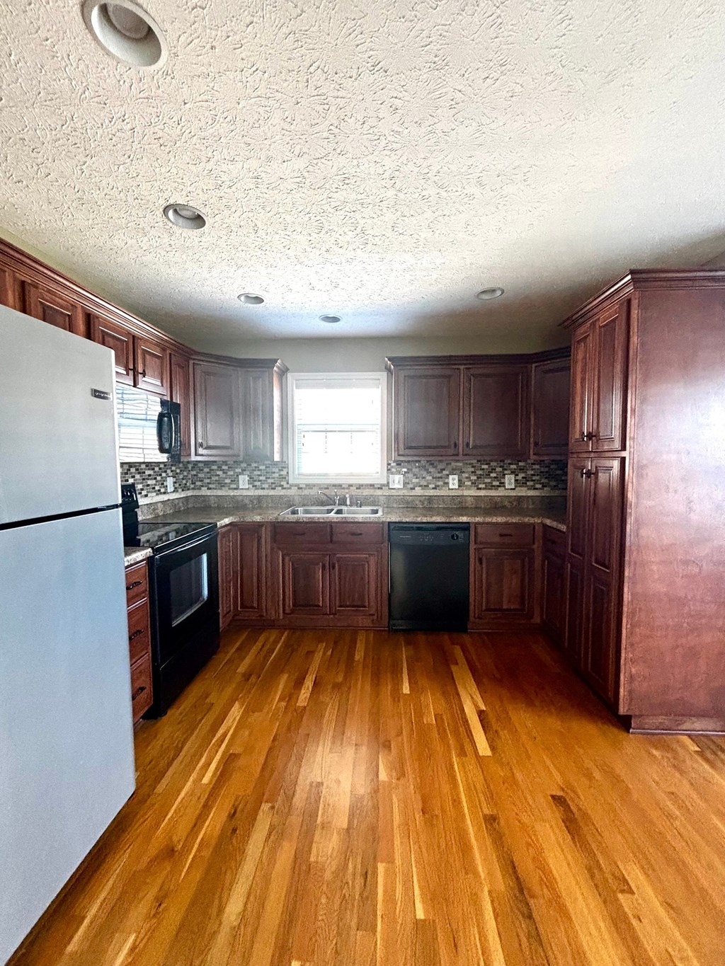 A kitchen with wooden floors and dark brown cabinets.