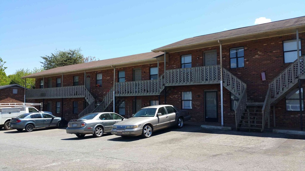 a parking lot in front of a brick building with cars parked
