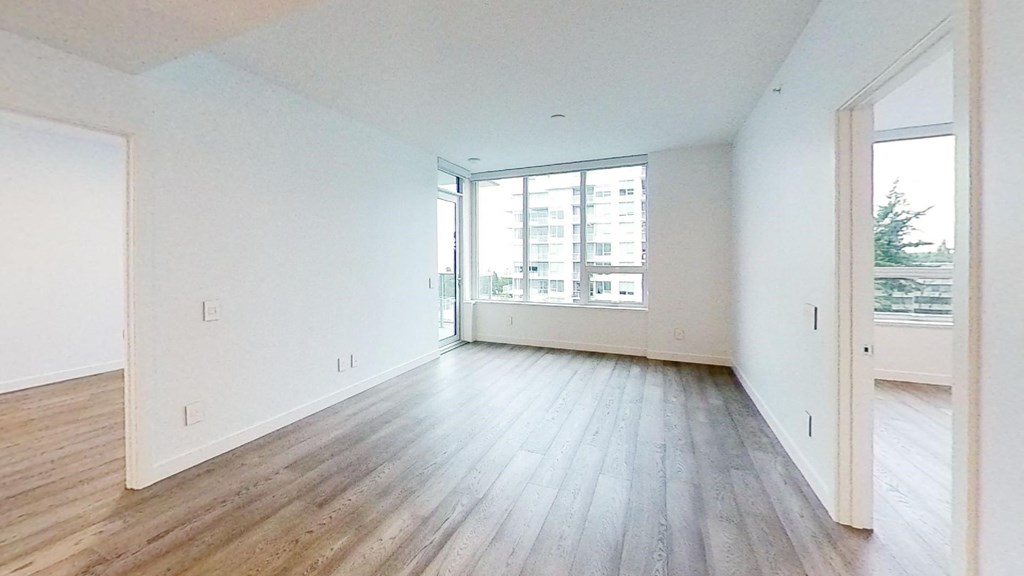 an empty living room with wood floors and a large window