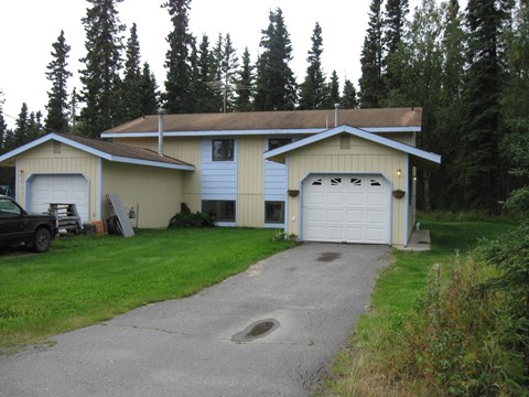 A house with a garage and a car parked in front.