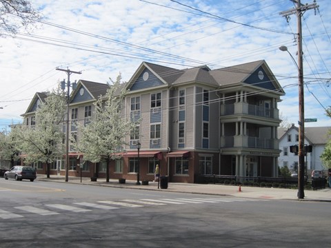 A large building with a red awning sits on the corner of a street.