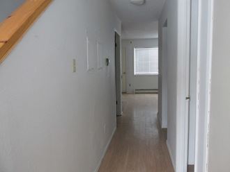 an empty hallway with white walls and wood floors