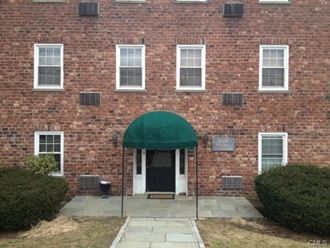 the front of a brick building with a green tarp over the door