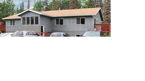 A grey house with a red fence and cars parked in front.