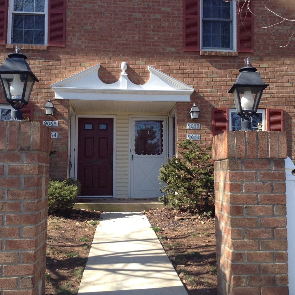 the front door of a house with a walkway and two lanterns