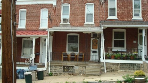 A red brick house with a white door and a small porch.
