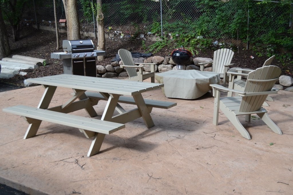a patio with a picnic table and chairs and a grill