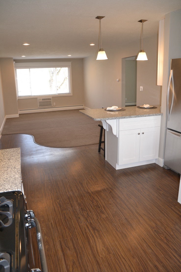 an empty kitchen and living room with wood flooring
