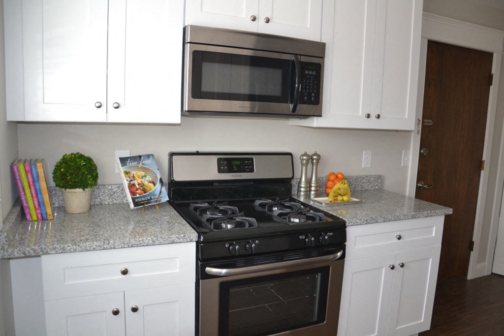 a kitchen with white cabinets and a stove and a microwave