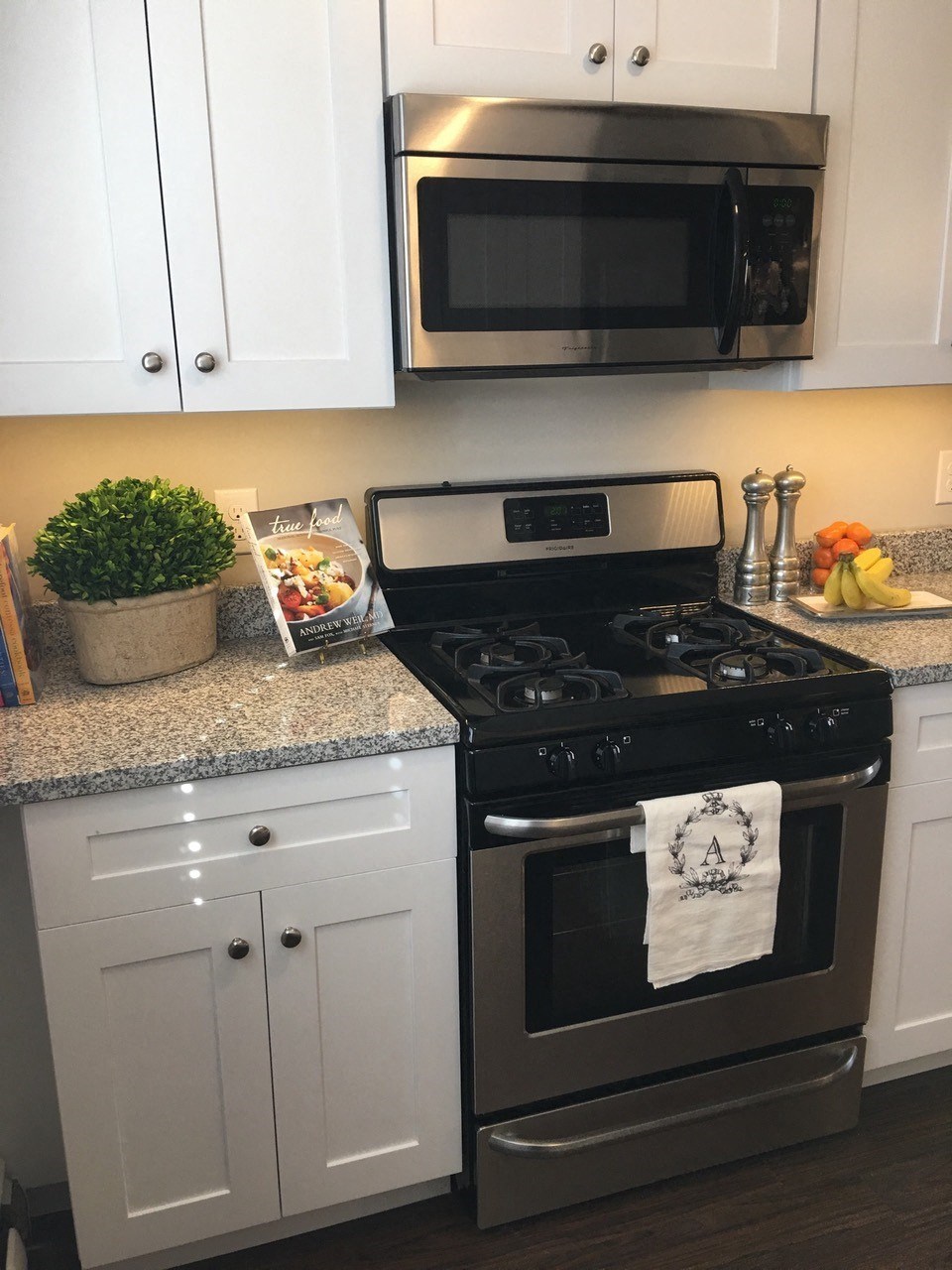 a kitchen with stainless steel stove and microwave and white cabinets