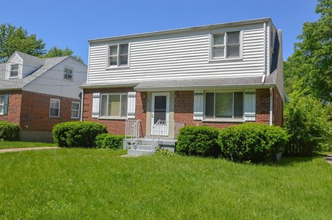 A house with a white siding and a brick facade with a small porch.