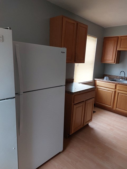 a kitchen with a refrigerator and wooden cabinets