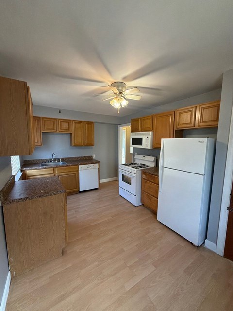 A kitchen with wooden cabinets and white appliances.