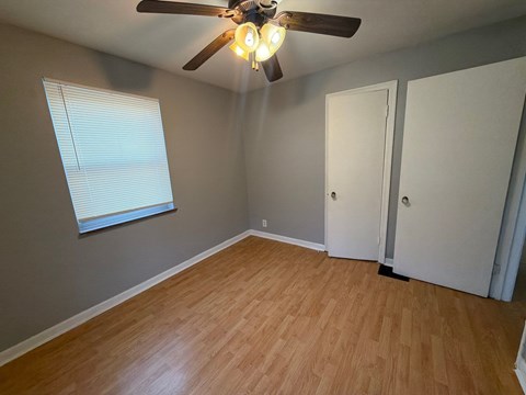 A room with a ceiling fan and wooden flooring.