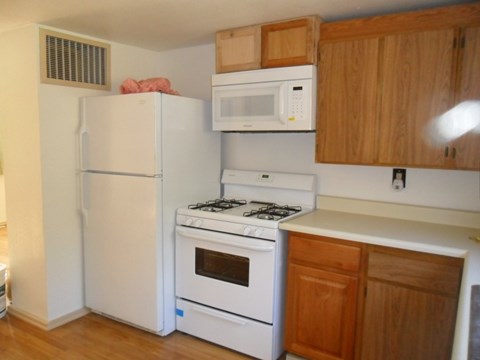 A white refrigerator and oven in a kitchen with wooden cabinets.