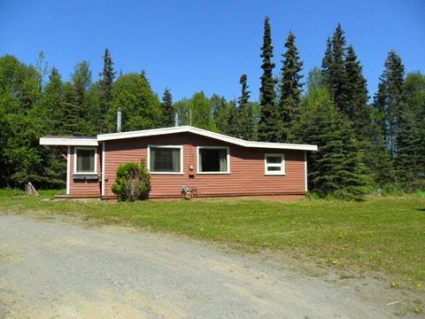 A house with a brown roof and a brown fence is surrounded by trees.