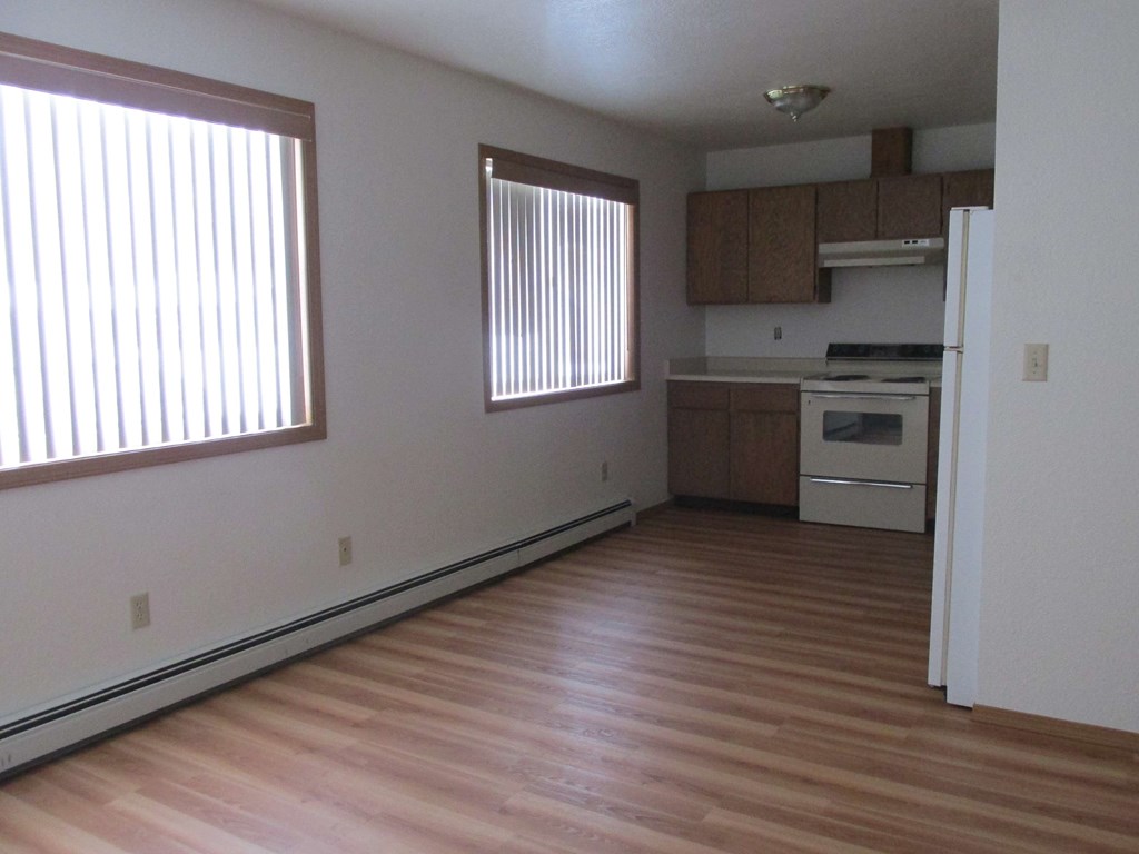 an empty living room and kitchen with wood flooring
