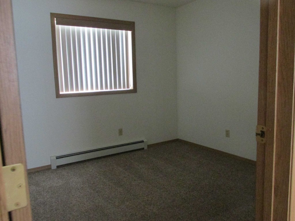 an empty room with a window and a carpet