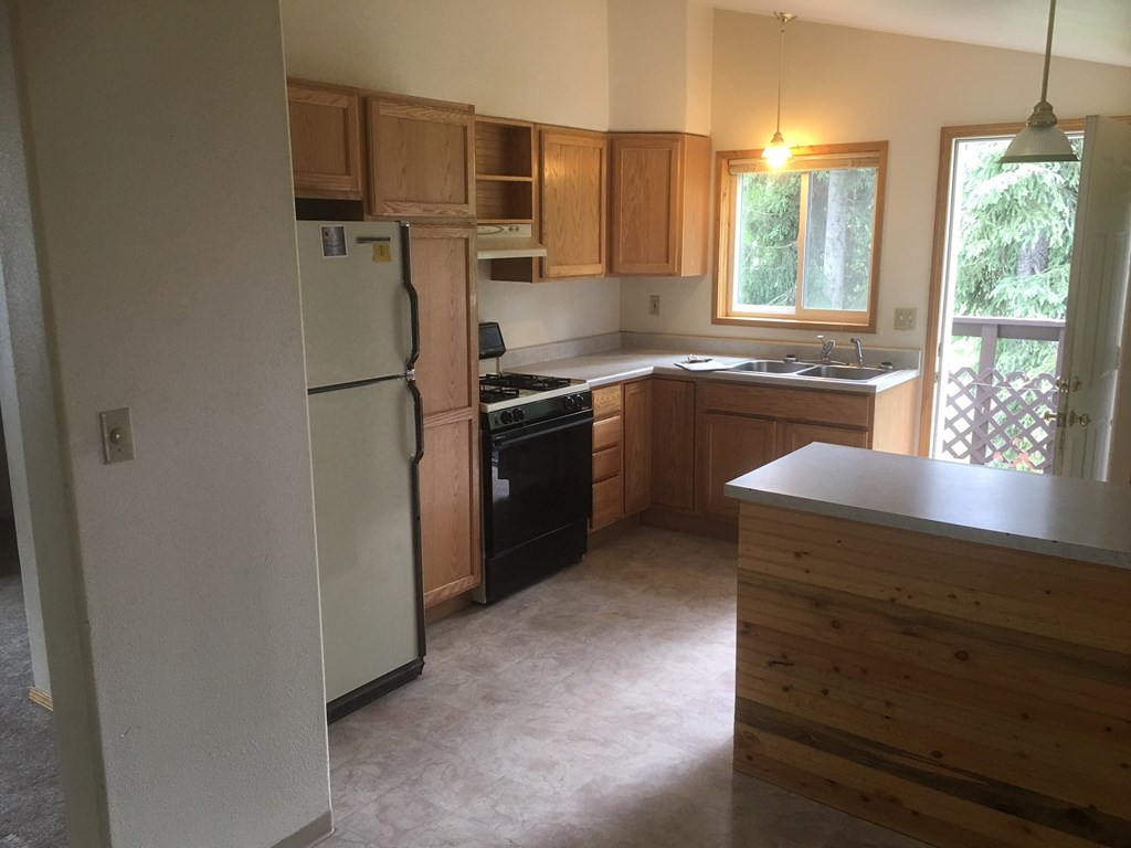 an empty kitchen with wooden cabinets and a white refrigerator