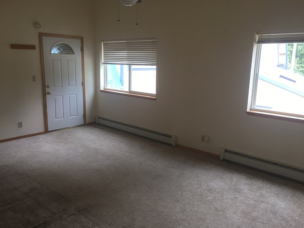 an empty room with two windows and a door