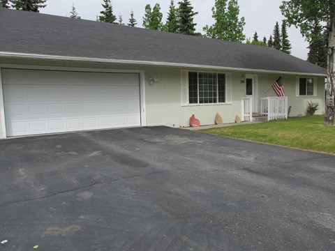 A house with a grey roof and a white garage door.