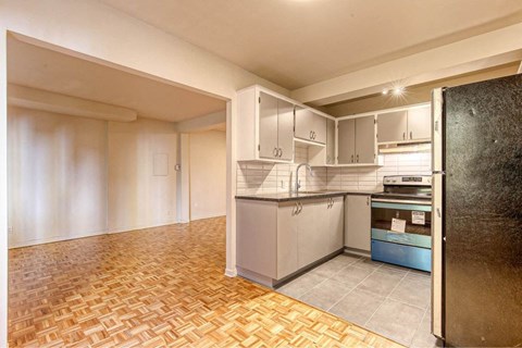 an empty kitchen with white cabinets and a refrigerator