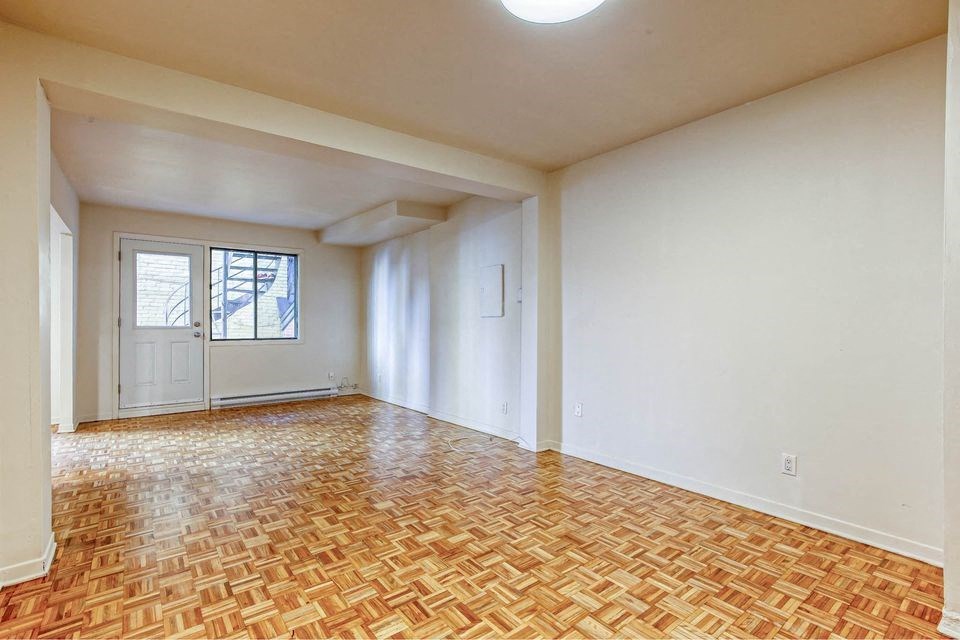 an empty living room with white walls and a wooden floor