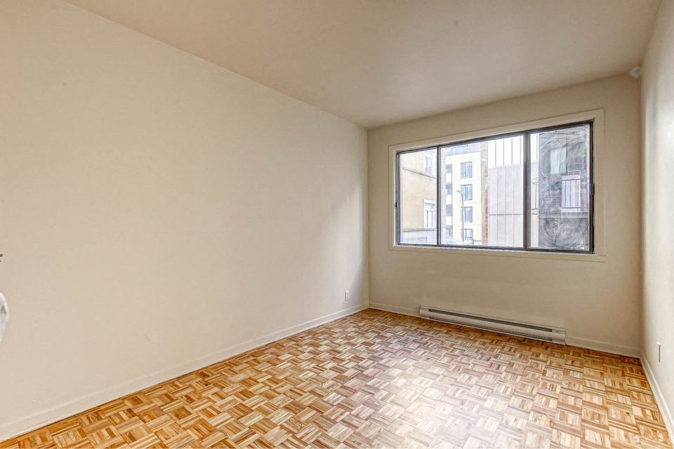 an empty room with a window and a wooden floor