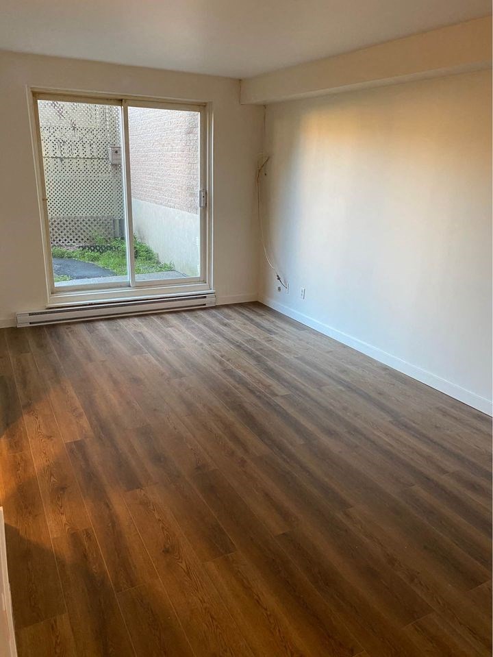 an empty living room with wood floors and a window