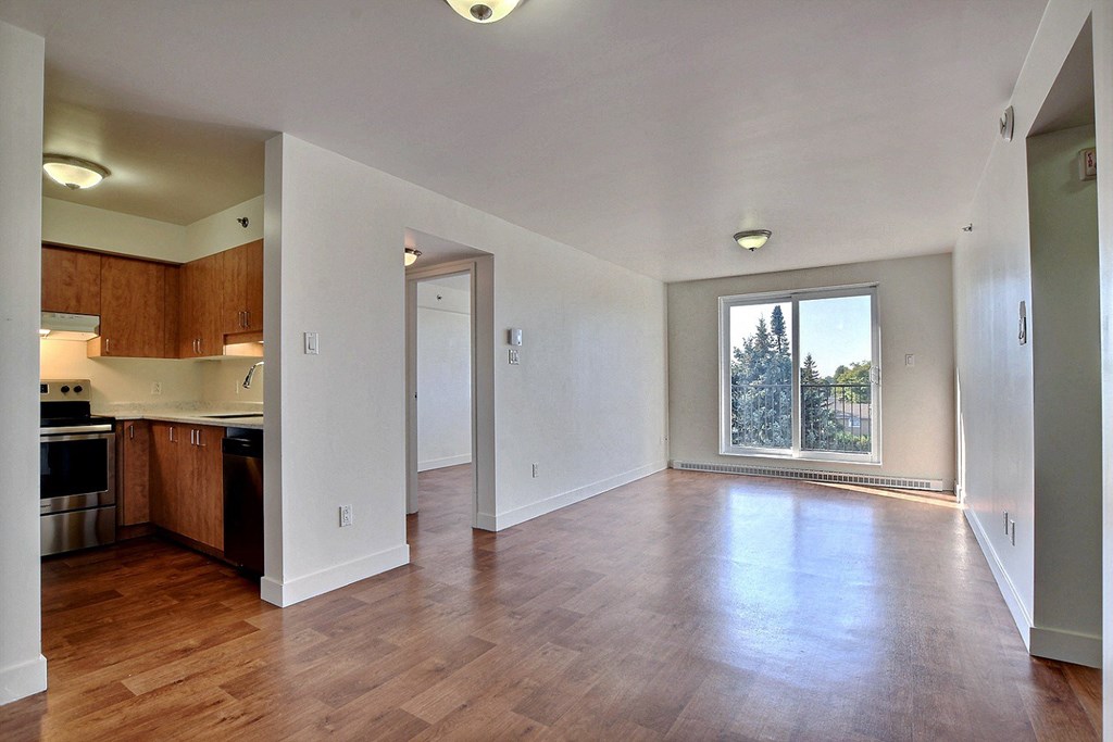 an empty living room and kitchen with a large window