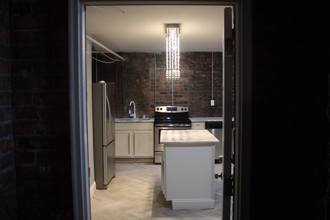 A kitchen with a refrigerator, sink, and cabinets.