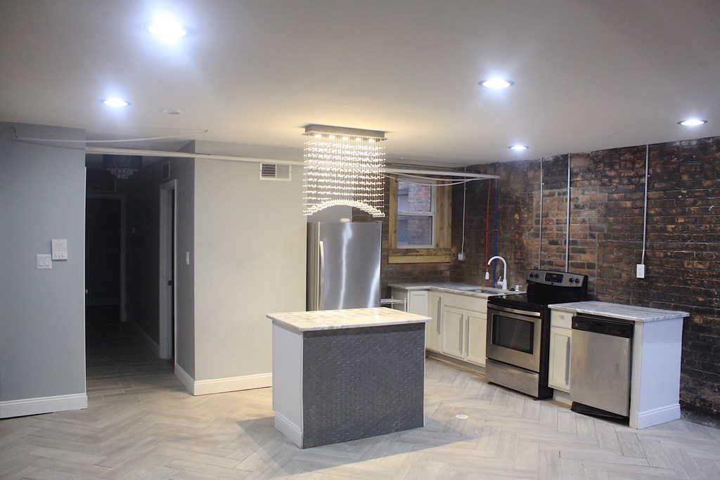 A kitchen with a brick wall and a white island.