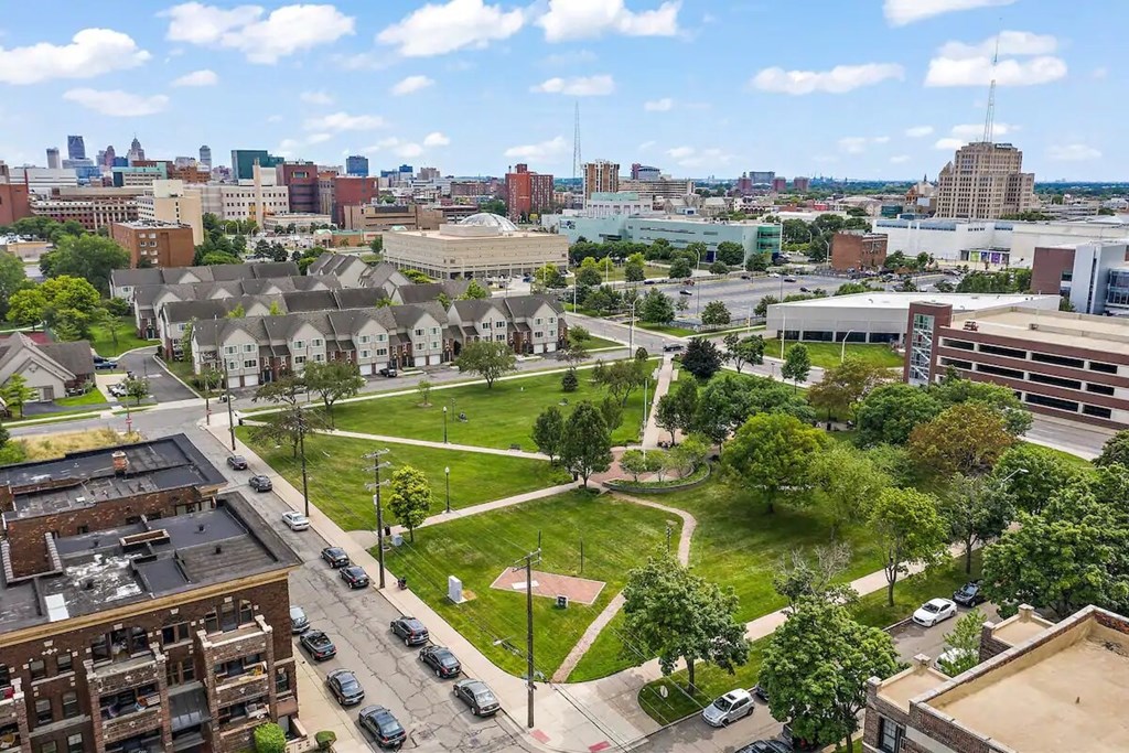 A cityscape with buildings, cars, and a green park area.