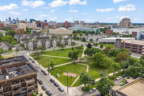 A cityscape with buildings, cars, and a green park area.