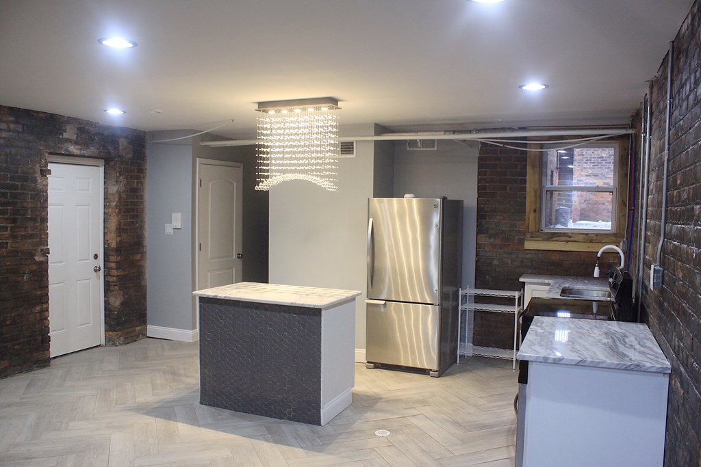 A kitchen with a refrigerator, stove, and island.