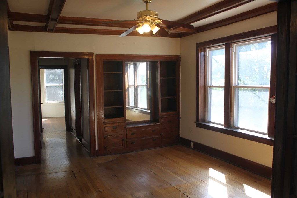 A room with a ceiling fan and wooden floors.