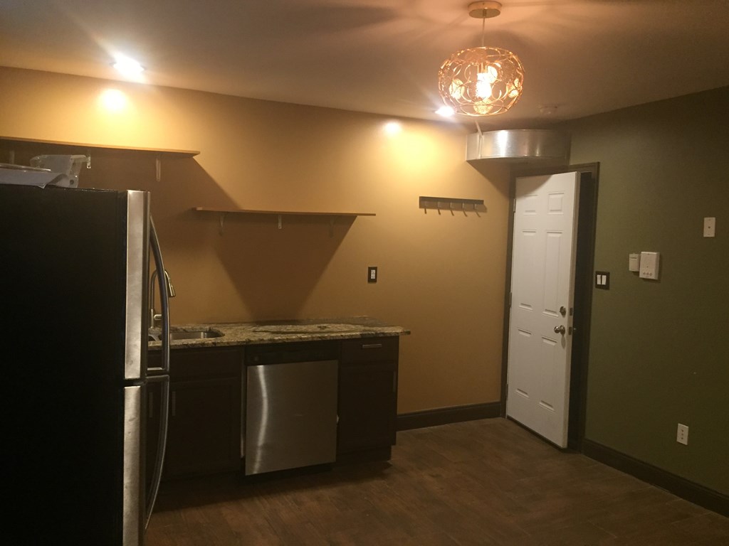A kitchen with a black refrigerator and a white door.