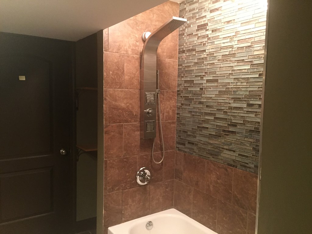 A bathroom with a tiled wall and a white bathtub.