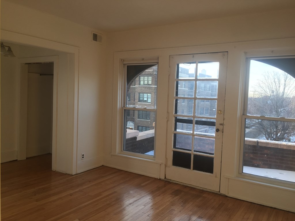 A room with a wooden floor and three windows.