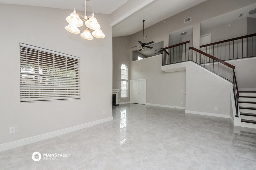 an empty living room with a staircase and a ceiling fan