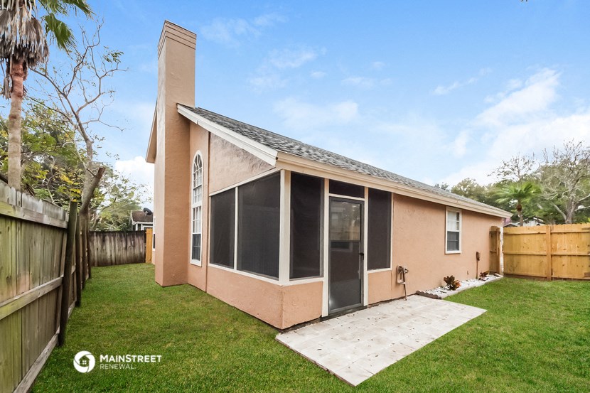 a small pink house with a yard and a fence