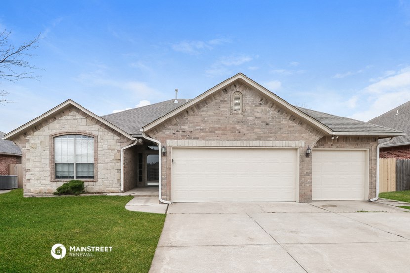 a brick house with two garage doors and a lawn