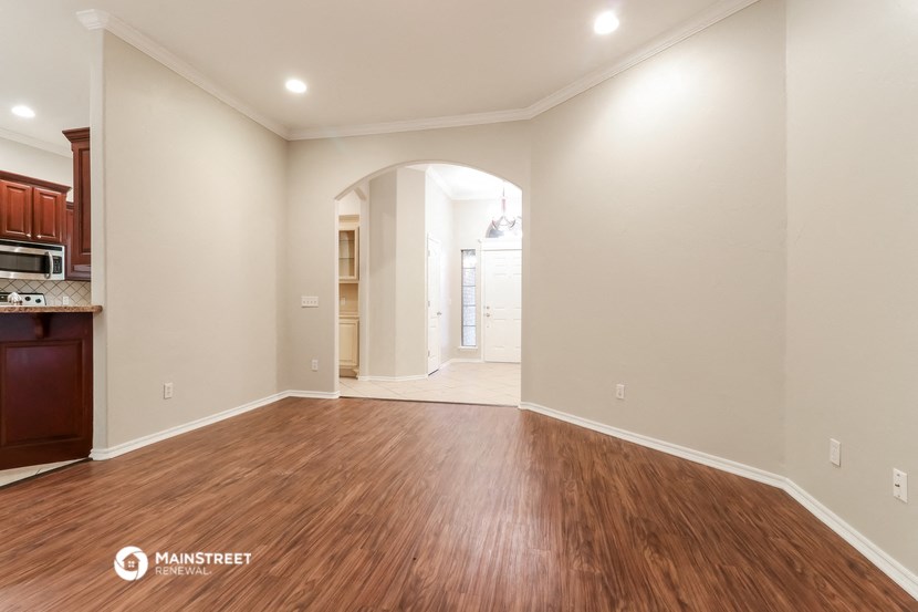 the living room and kitchen with wood flooring and white walls