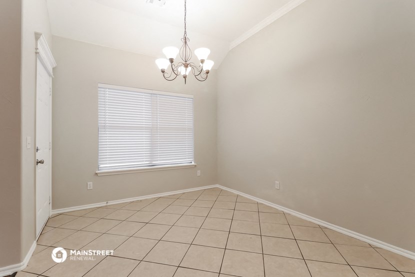 the dining room of an empty home with a chandelier