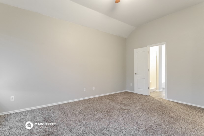 the spacious living room with carpeting and a door to the bedroom