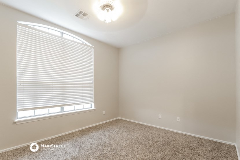 the upstairs bedroom has a large window and carpeted flooring