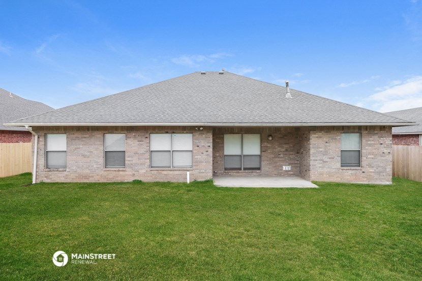 a brick house with a gray roof and a grassy yard