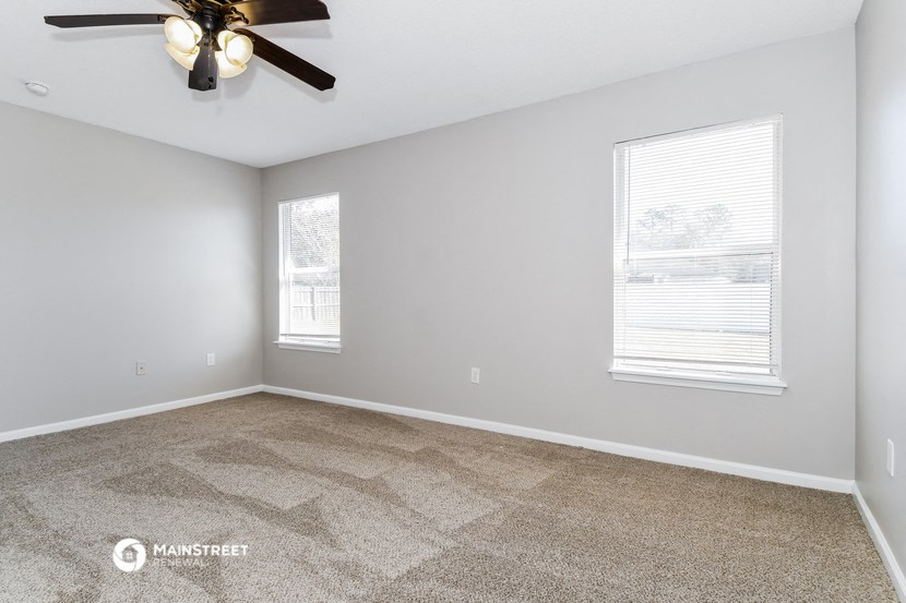 the spacious living room with carpeting and a ceiling fan