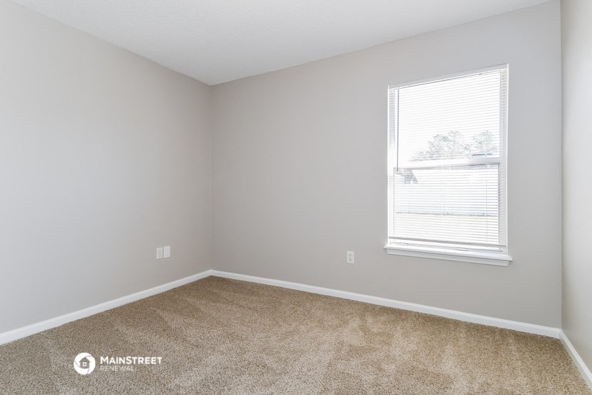 a bedroom with a window and carpeting